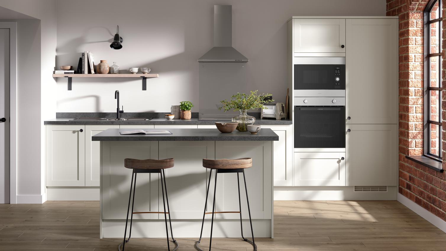 A shaker kitchen in a light white colour and single-wall layout. There are dark stone worktops and matching breakfast bar.