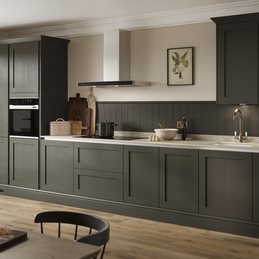 A modern shaker kitchen idea with handleless green cupboard doors. Includes silver metal profiles and a built-in, black oven.