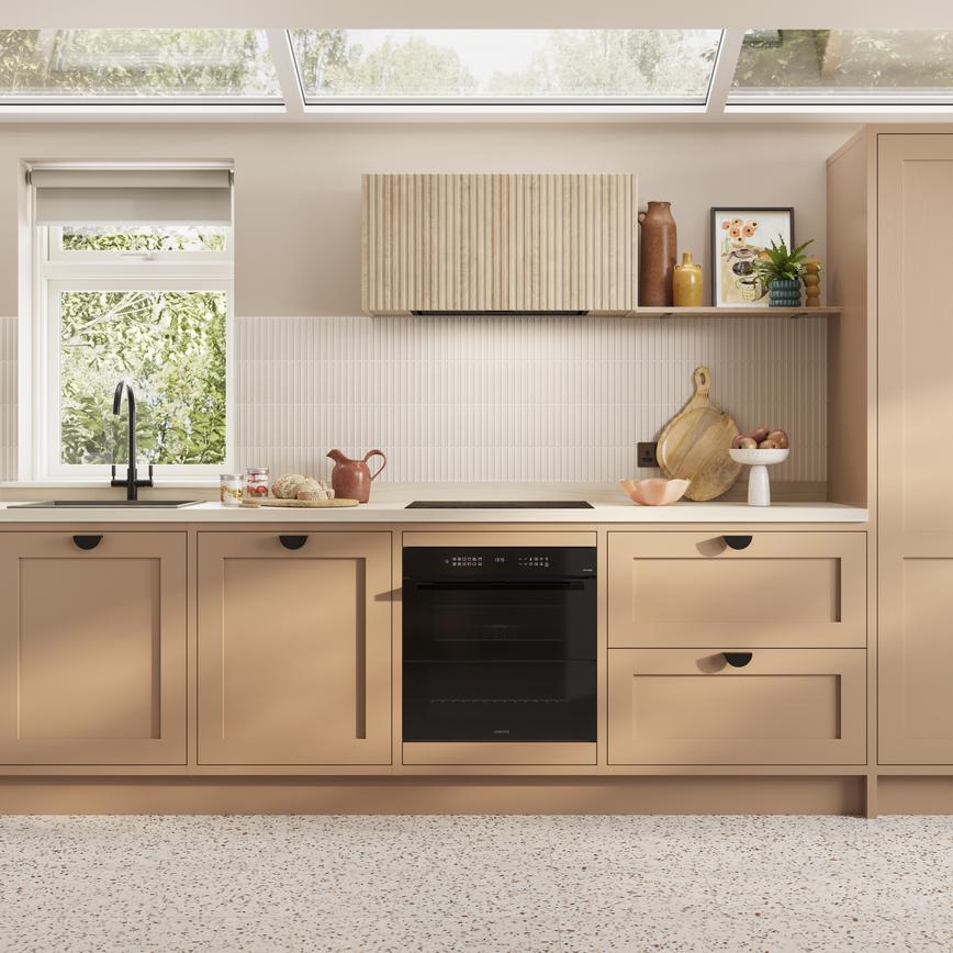 A single wall kitchen featuring teracotta shaker doors. Styled with black handles, a white worktop, and built-under oven.
