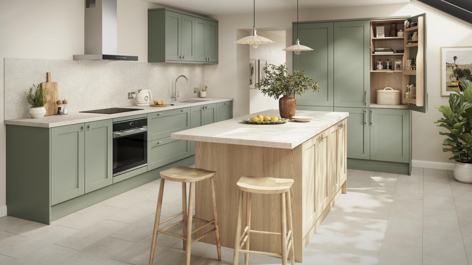 A shaker kitchen in a reed green colour, with wall units and larder cabinet. An oak-colour kitchen island is in the middle.