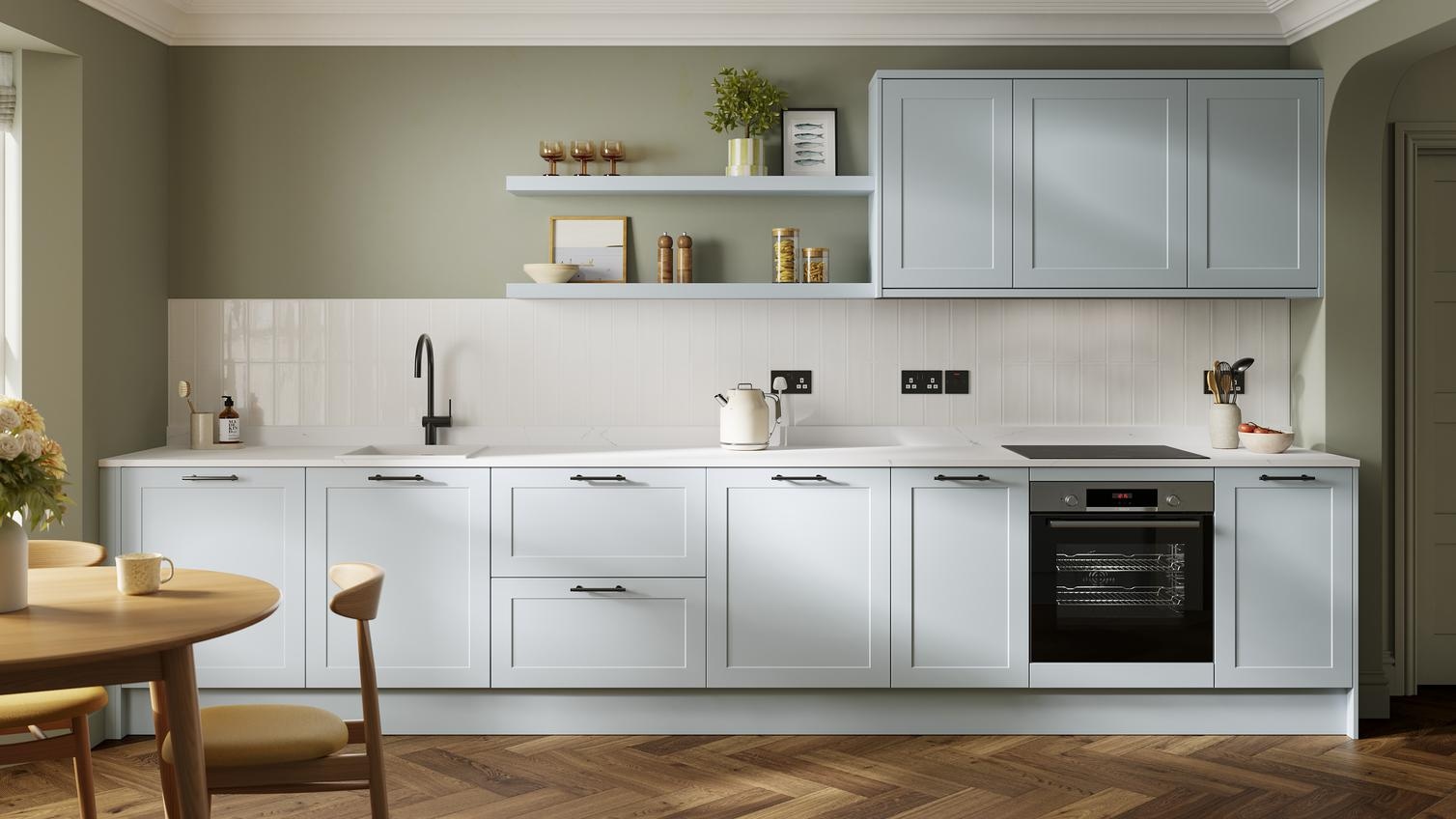 A pale mist-blue shaker kitchen in a single-wall layout. It has matching wall cabinets and dark oak herringbone flooring.