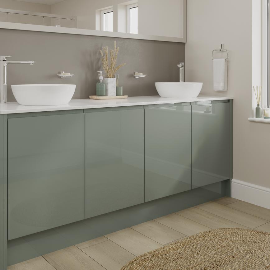 A Green Gloss Bathroom, With Slab Fronts And Integrated Handles. It Is Finished With A White Worktop, Wall Mirror, And Sinks