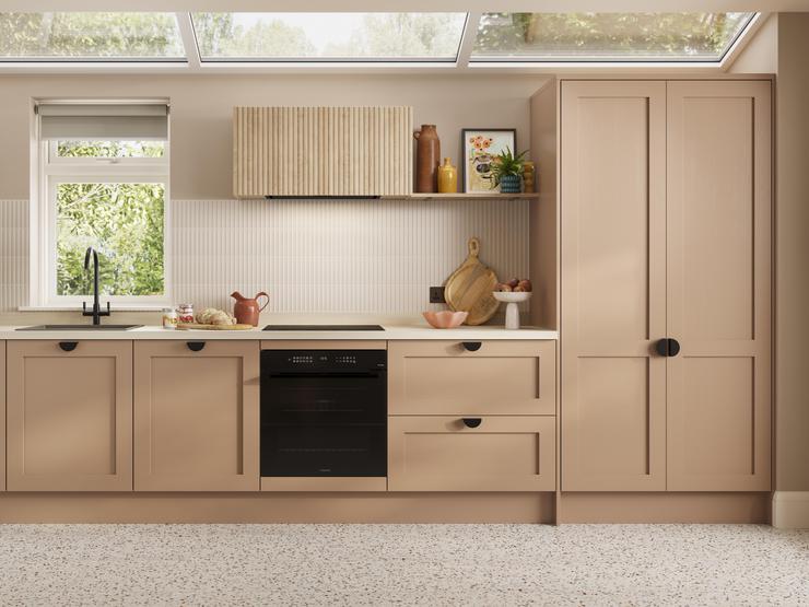 A shaker terracotta kitchen from the Chilcomb collection. It is in a single-wall layout and has rounded black handles.