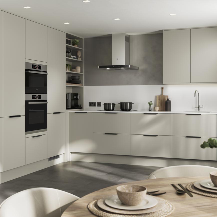 L-shape modern kitchen design with neutral slab cupboards in a matt finish. Includes two-drawer units and black bar handles.